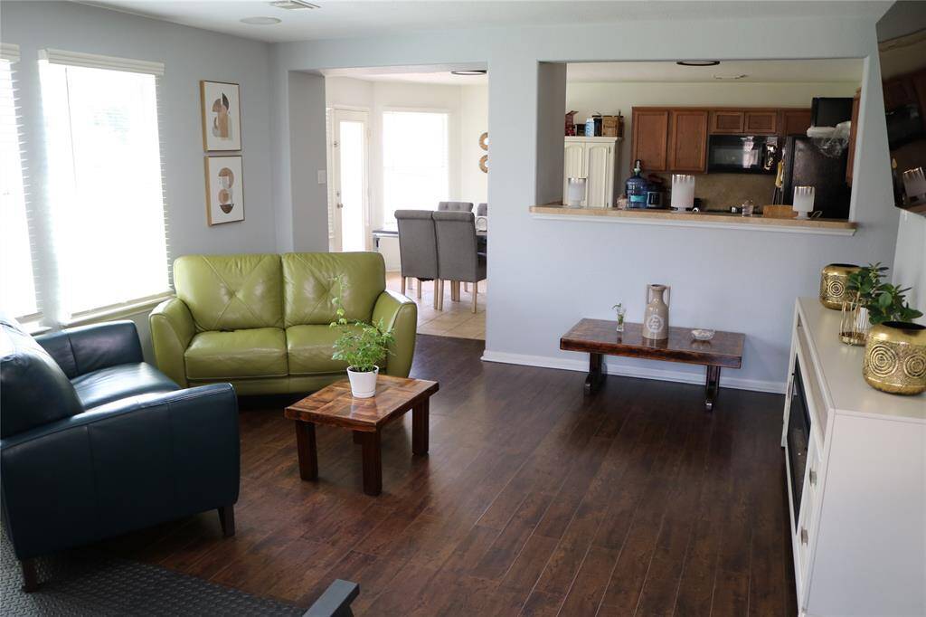 This versatile living room that flows into the area kitchen offers the perfect space to relax or work out, with abundant natural light pouring in through large windows.