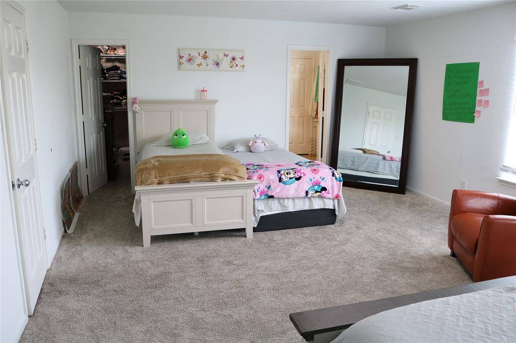 The spacious primary bedroom offers neural wall and carpeted flooring with two doors offering easy access to the bathroom and closet.