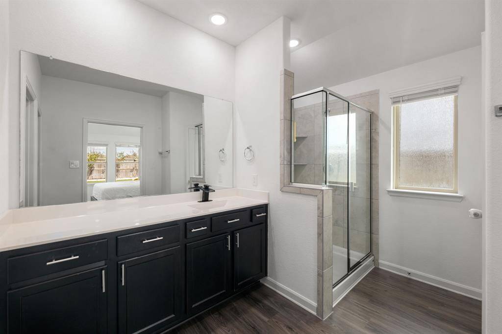 This primary bathroom is definitely move-in ready! Featuring a steel framed walk-in shower with tile surround, dark stained cabinets with light countertops, spacious walk-in closet with shelving, high ceilings, neutral paint, sleek and modern finishes.
