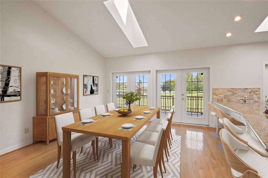 Here is a close-up photo of the generously sized dining area, virtually staged, showing that the large space can accommodate a large table, multiple seating, bar stool seating along the kitchen counter top, and dining room furnishings such as a china cabinet or buffet.  Natural light shines from above through the well placed skylights.