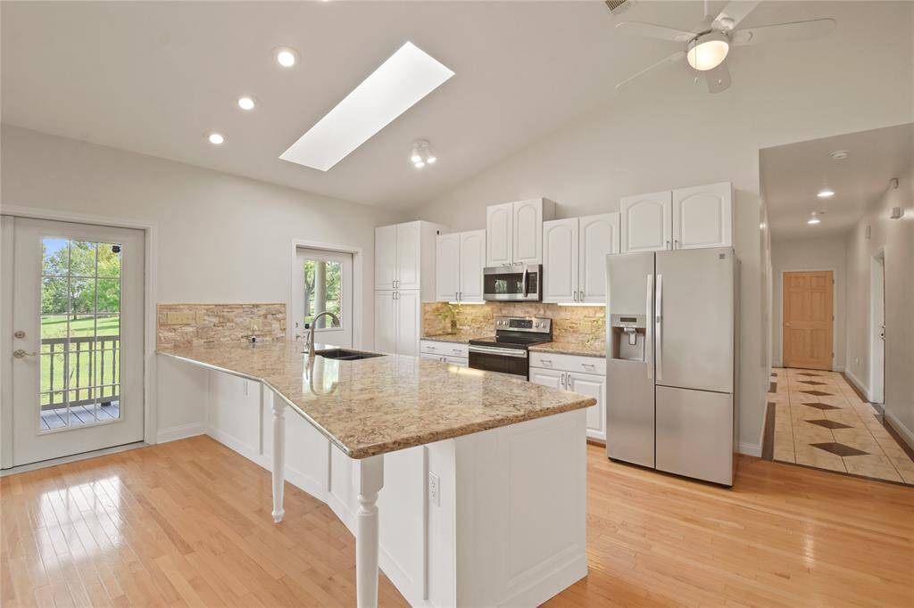The bright, cheerful kitchen features updated cabinetry, granite countertops and stone backsplashes, deep dual well sink; and stainless steel appliances including a glass top Ceran style electric range, microwave oven, dishwasher, and side by side refrigerator/freezer.  What a pleasure to cook with views out over the property and lake!