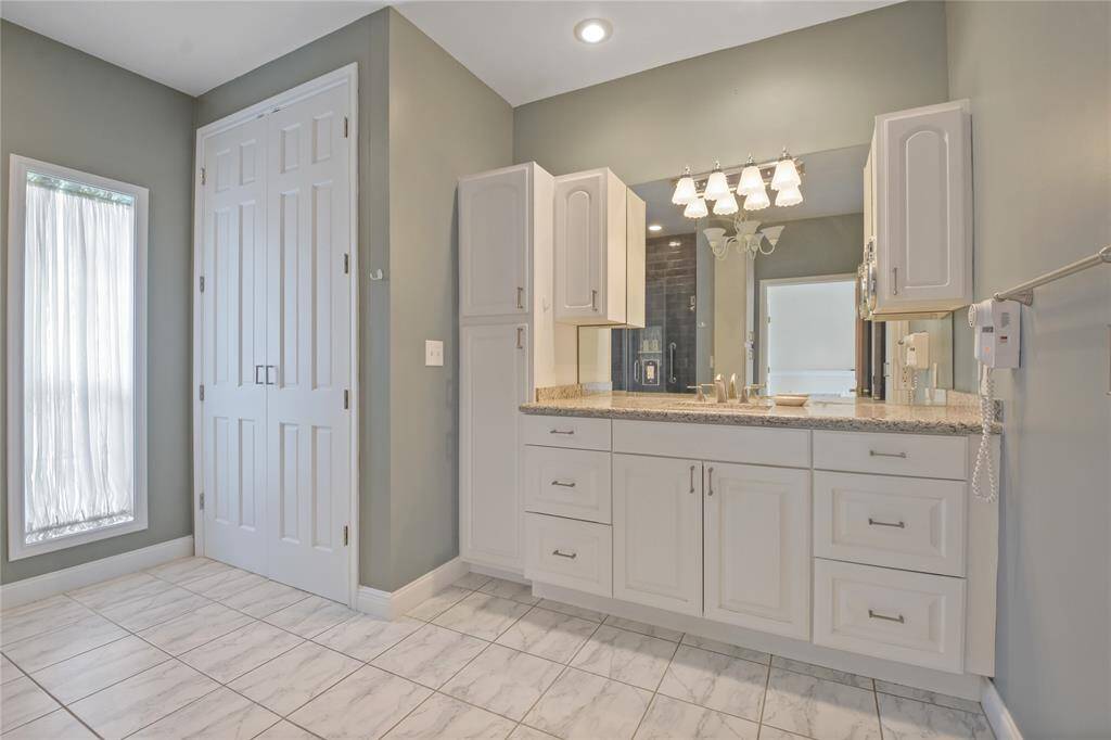 The renovated Primary bath has the coloring of a tranquil spa.  Bright, white cabinetry provides excellent storage. There is plenty of counter space also.  To the left is a wonderful storage closet with many uses!