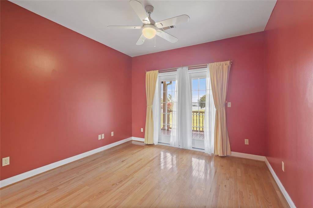 Down the hallway from the kitchen and living area, one will find two bedrooms and a hallway full bath.  This is the first of the bedrooms.  It has hardwood flooring and French door access out to the long, covered porch area at the rear of the home.