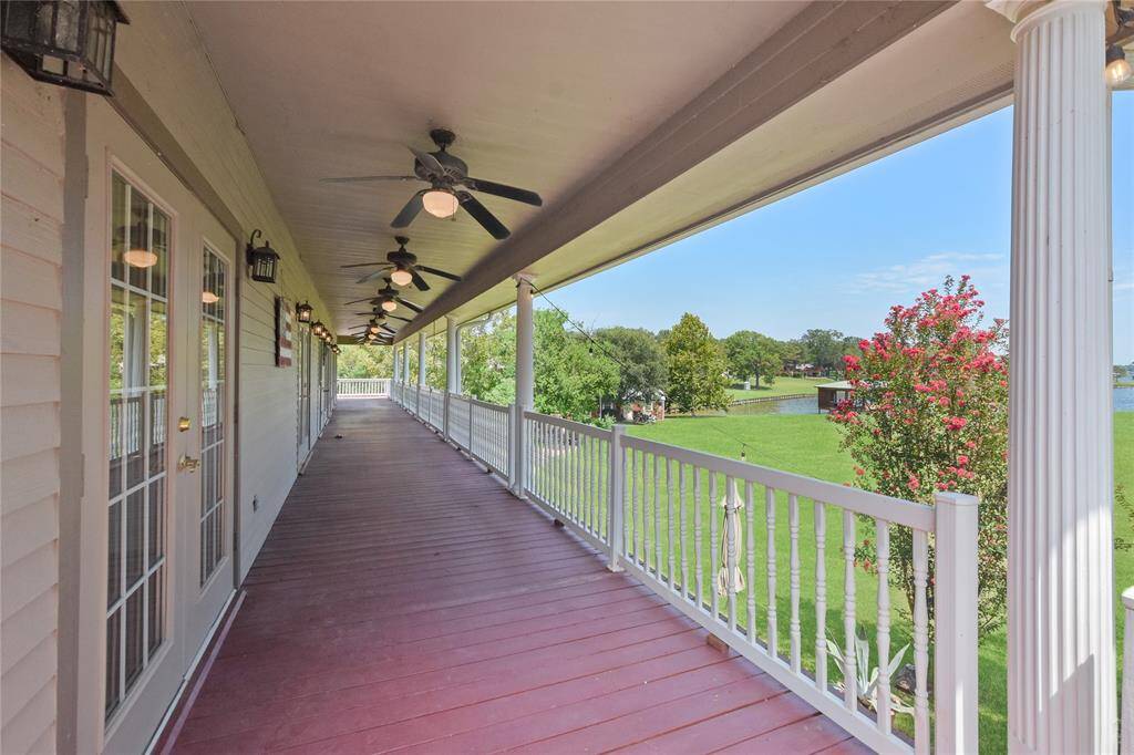 This long, covered patio/deck flows across the main level at the rear of the home.  Entrance out onto this wonderful outdoor space may be had from several rooms via the French doors as shown.  What an excellent place to enjoy a cup of coffee or tea in the morning, or a glass of wine or cocktail in the evening staring out at the massive yard area and lake beyond.