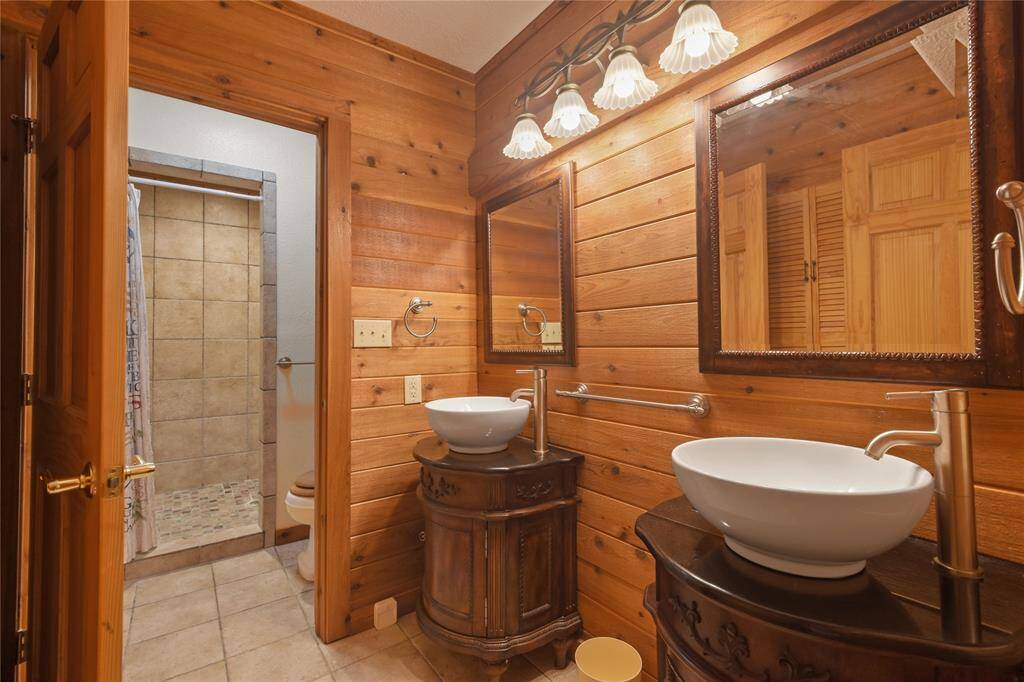 This is the second full bathroom on the downstairs level and includes double sinks and vanities, mirrors, and a separate "wet" area for shower and commode.