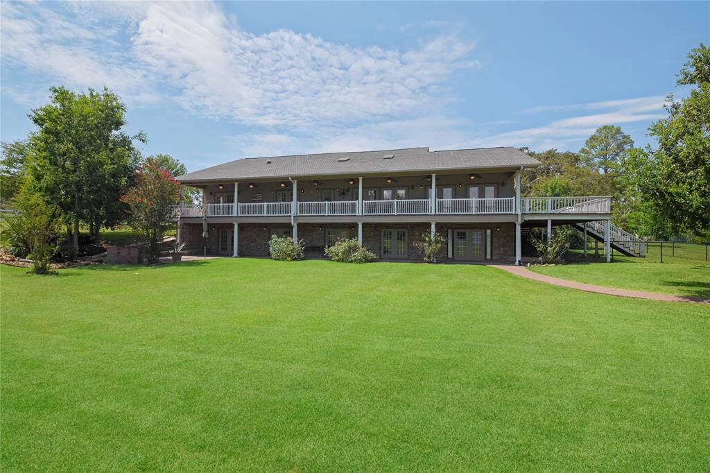The backside of this lovely home, surrounded by beautiful lawn areas perfect for kids and pets play. Note the amazing covered decking and patios. Lots of covered space to sit and enjoy watching over the lake and property. Mosquito control system helps you enjoy the outdoors around the house "bug free."