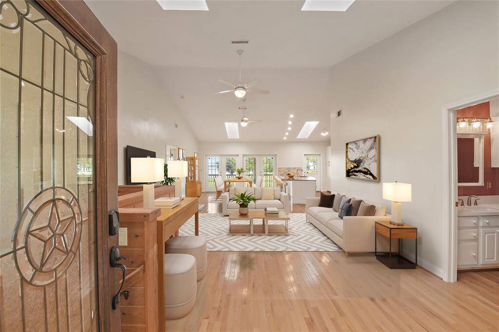 Entering inside, one is greeted by soaring ceilings and amazing natural light via several skylights.  A wide expanse of space which may be configured as one wishes and needs.  This room is virtually staged here showing what a living area and then dining area might look like.  To the right is a powder half bath, convenient for guests!
