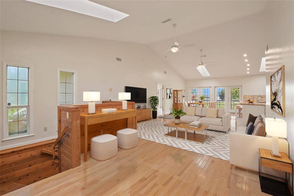 Upon entering, there is a stairway down to the lower level.  Shown here, and virtually staged is an open concept living area with dining area and kitchen beyond.  There is hardwood flooring throughout this area, high ceilings, and plenty of natural light.