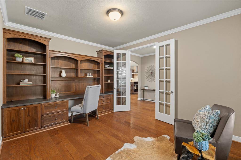 This home office is ready to inspire! A custom wood desk with built-in cabinets and shelves offers both function and style. The 8-foot sparkling French doors provide privacy while creating a serene space to read, work, or plan your next adventure.