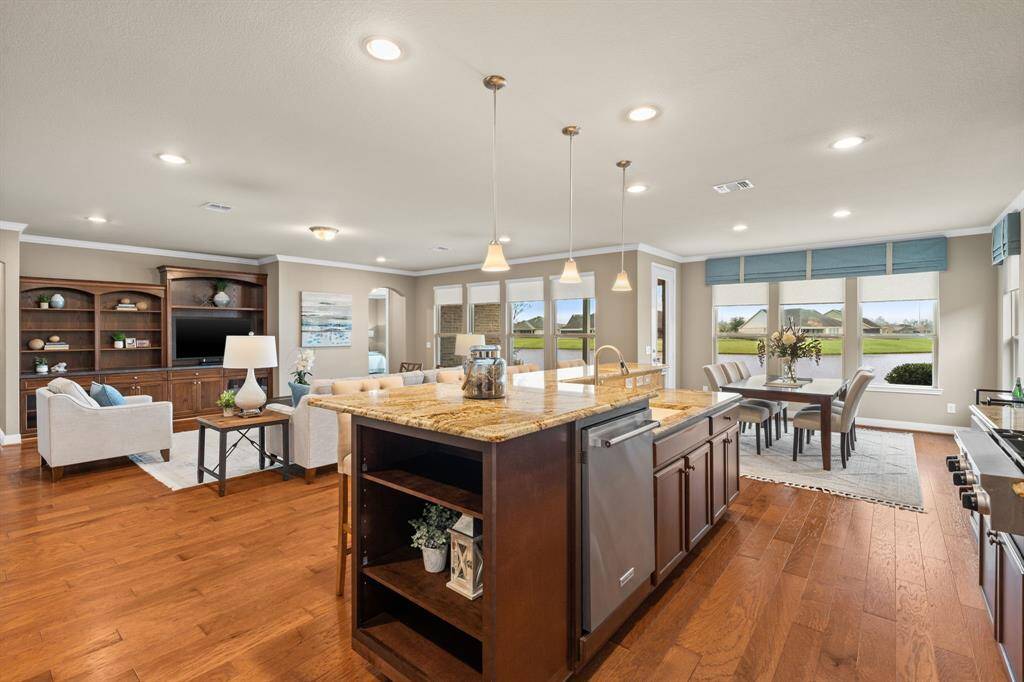 Beautiful wood flooring graces this exquisite home. As you step into this inviting space, you'll notice the seamless flow from gathering room, through the dining room and into the kitchen. The open bookcase on the ends can hold your favorite cookbooks or display your fun collectibles!