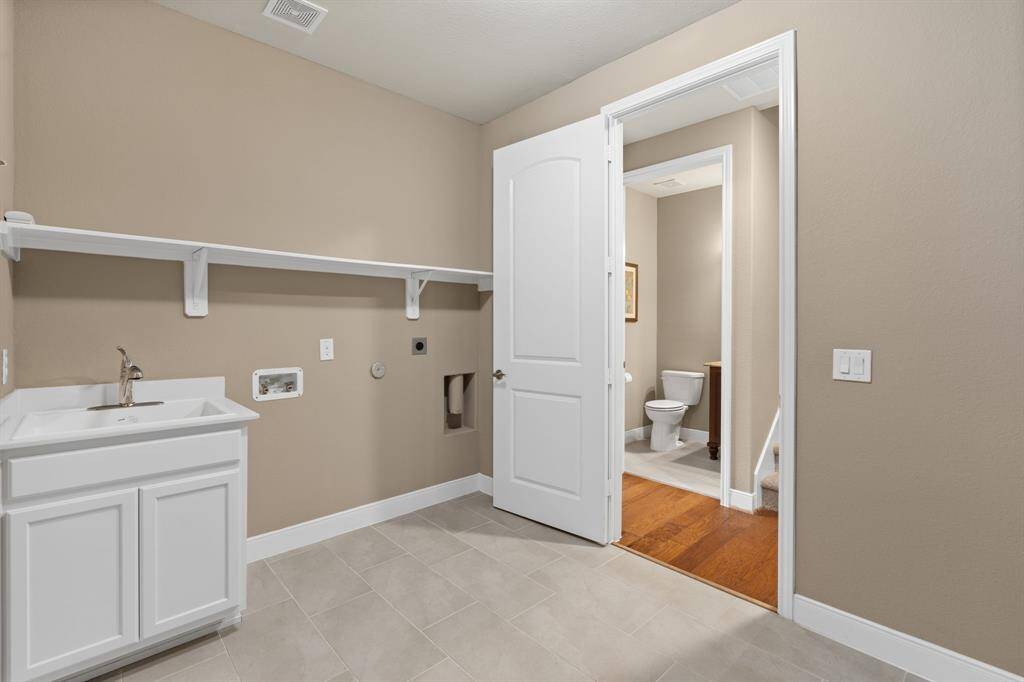 A sink, perfectly positioned for convenience, adds to the functionality of the room. Cabinets provide ample storage, keeping the space clutter-free and organized. BONUS: FLUSH ENTRY FROM GARAGE INTO HOME. NO STEP UP OR DOWN!