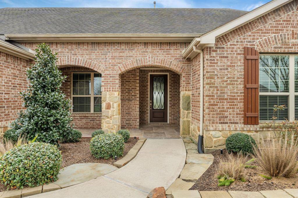 Stunning curb appeal! Mature landscaping and Texas stone accents frame the walkway, leading to a welcoming entry. The brick & stone archways add timeless charm, while the flagstone porch creates a grand first impression. The porch offers ample space for relaxation and a warm embrace. The wood ceiling planks add a touch of rustic charm and sophistication, creating an atmosphere that's both inviting and timeless.