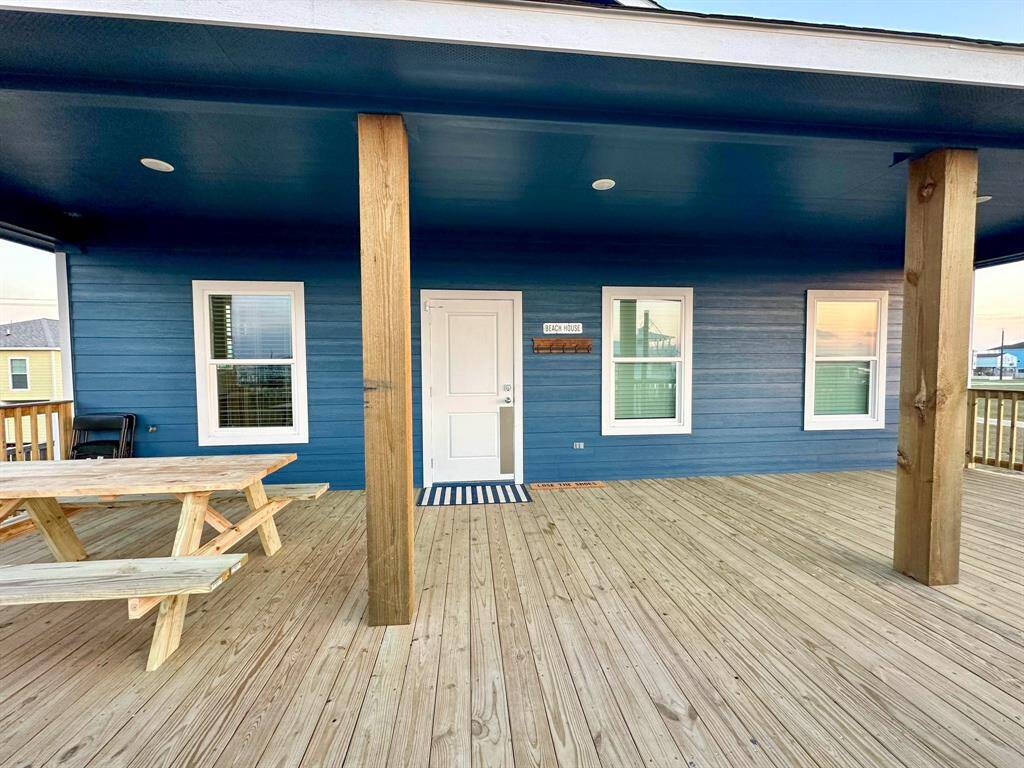 This photo showcases a charming blue house with a spacious wooden deck, featuring a picnic table and inviting entryway. Perfect for outdoor relaxation and entertaining.