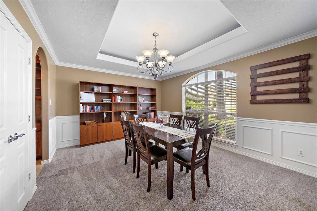 Dine in elegance with a formal dining room featuring tray ceilings and a delightful view of the front yard.