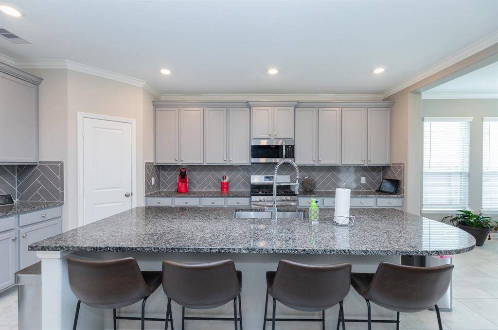 large granite island, bar seating, and sleek gray cabinetry