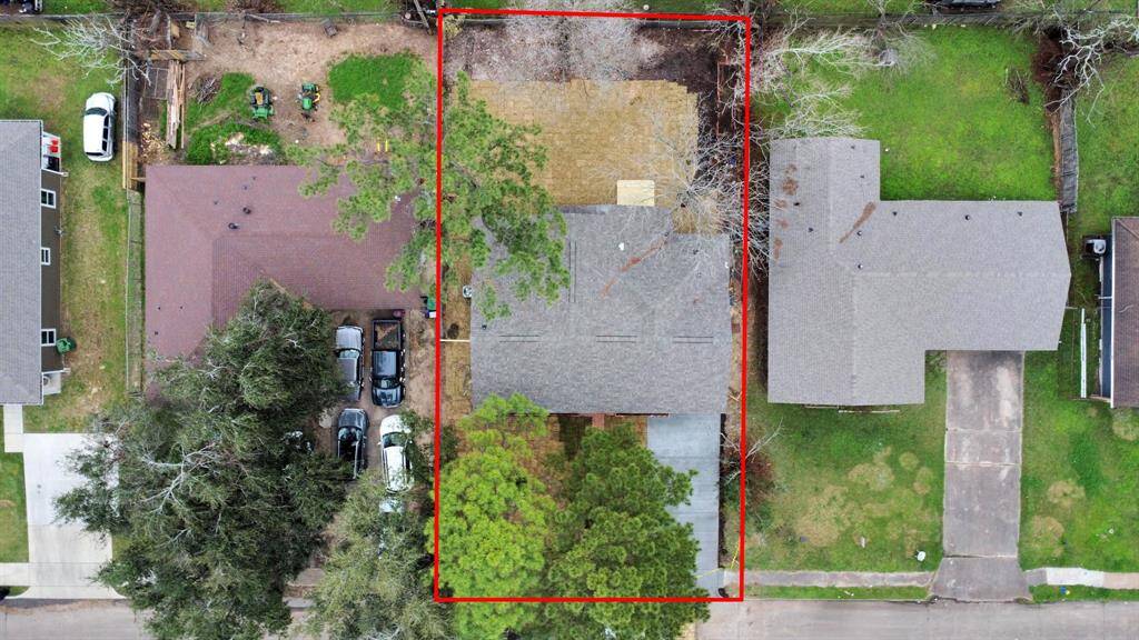 This aerial view shows a property with a rectangular lot outlined in red. . The backyard appears spacious, offering potential for landscaping or outdoor activities.