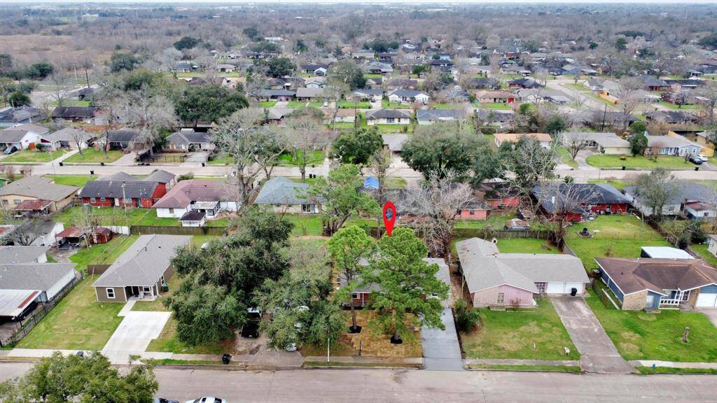 This aerial photo showcases a suburban neighborhood featuring single-family homes with spacious yards and mature trees. The highlighted property is centrally located, offering a blend of privacy and community. The area appears well-maintained, with nearby streets and amenities visible.