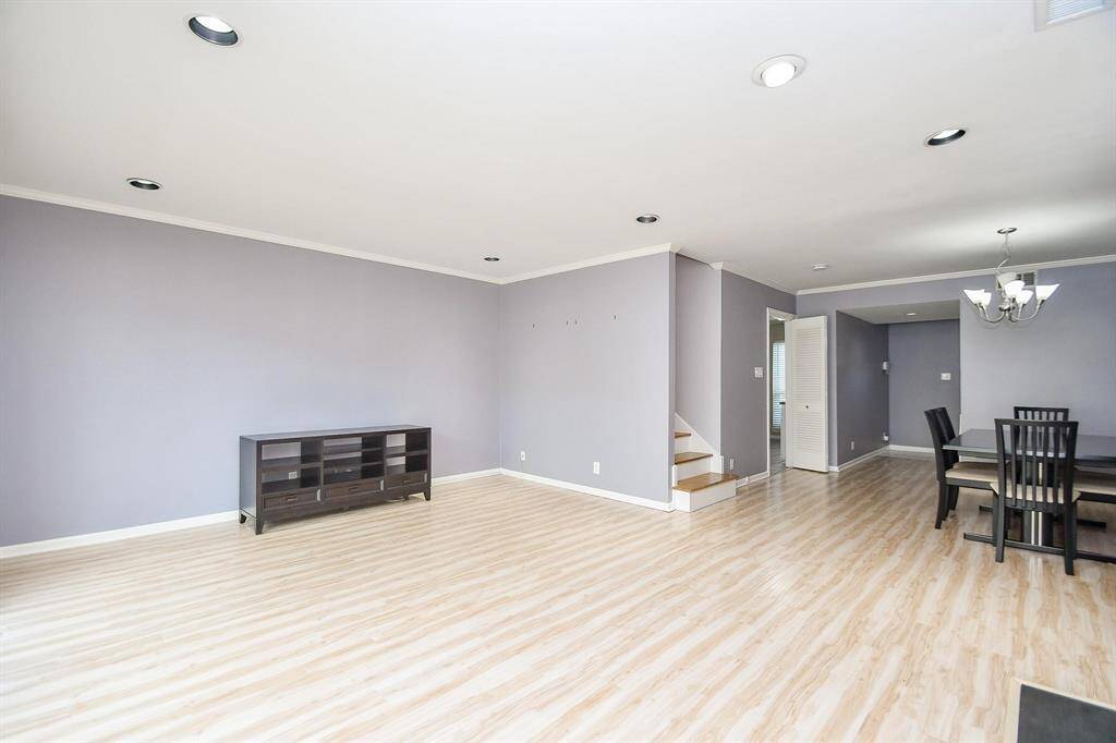 This photo showcases a spacious open-concept living and dining area It features recessed lighting, a compact staircase. The room is bright and inviting, ideal for entertaining or family gatherings.