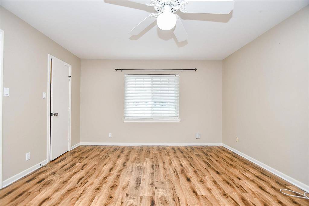 Bright room with neutral walls, vinyl wood flooring, and a ceiling fan. Features a window with blinds. Suitable for a bedroom or home office.
