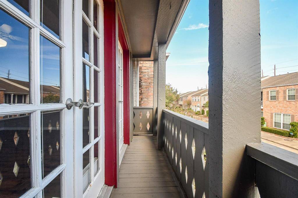 Cozy balcony with elegant wooden railings, French doors, and a scenic neighborhood view—perfect for relaxation.