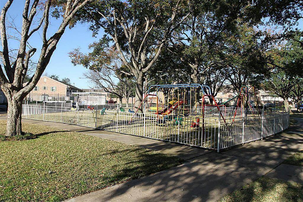 Fenced playground area with various play structures, surrounded by trees and grass. It's located just steps away providing a family-friendly environment.