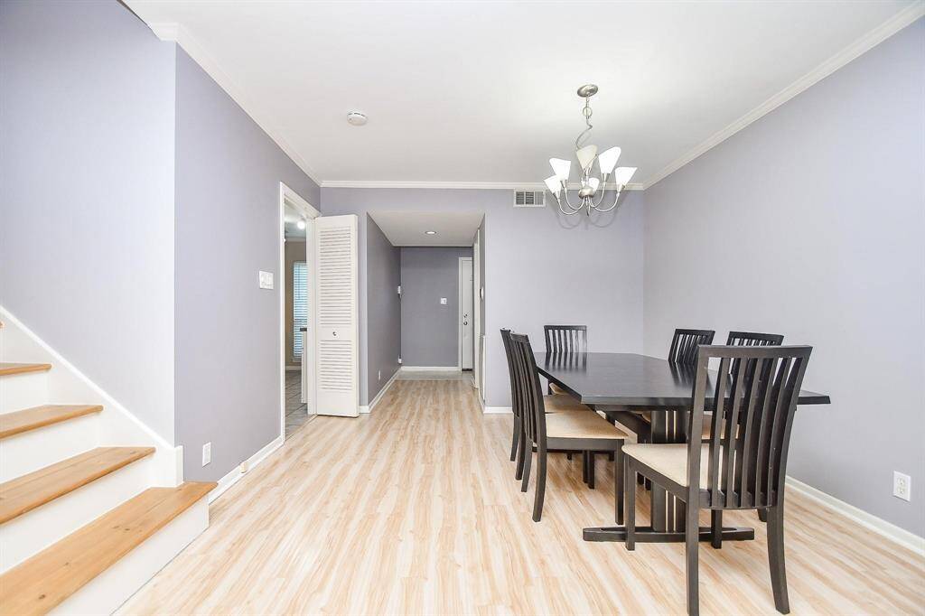 Bright dining area with beautiful light colored laminate wood flooring and soft gray walls. An adjacent staircase lead to other parts of the home, adding to the open and inviting layout.