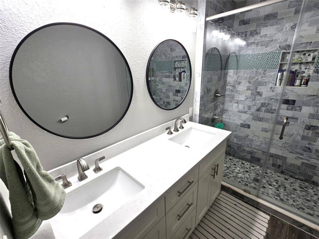 Primary bath has two sinks and a custom walk-in shower