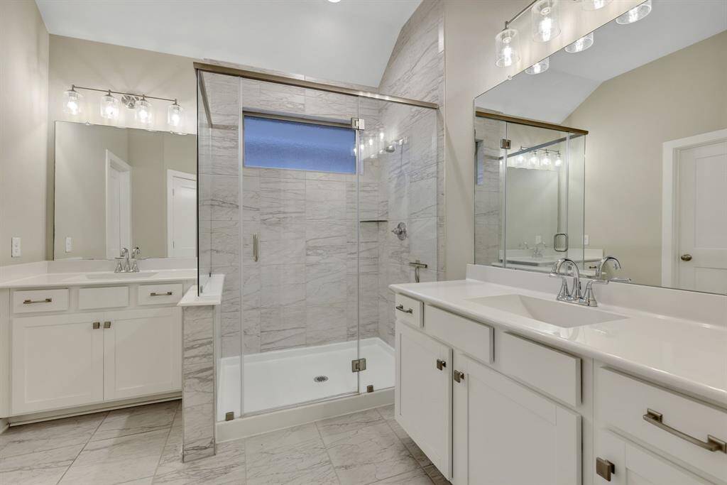 Primary bathroom boasts dual sinks, large separate shower and beautiful tile