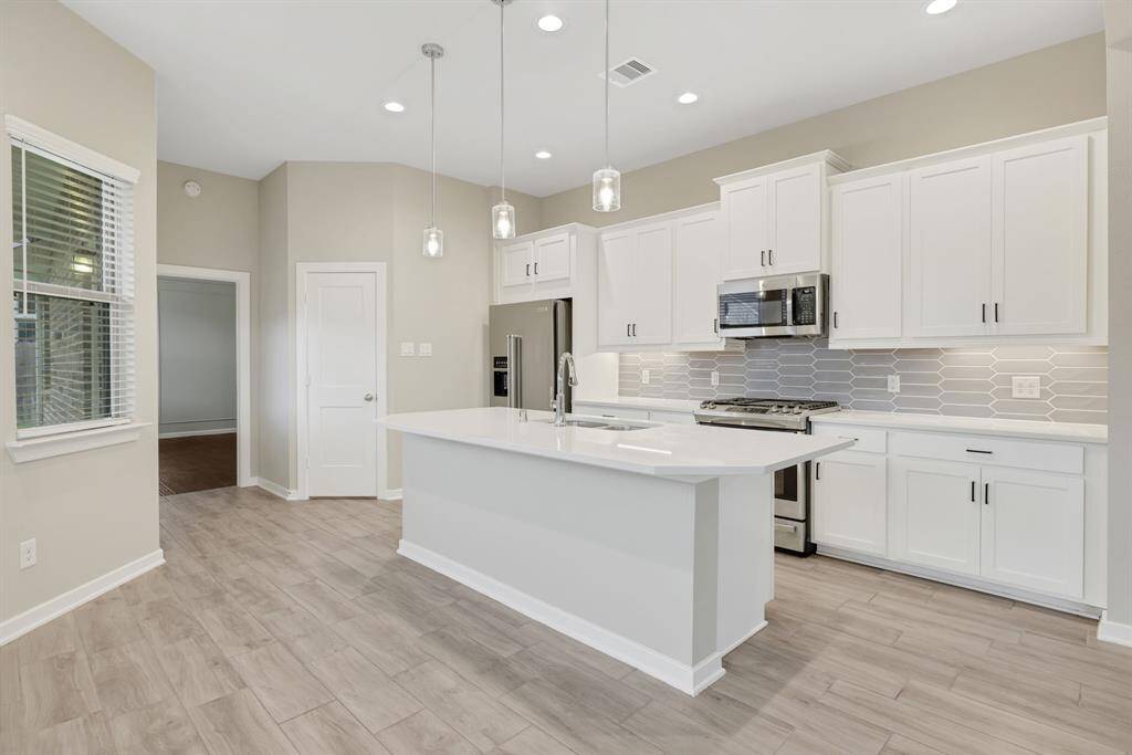 Kitchen is white with beautiful light gray tiled backsplash, stainless steel appliances and gas range with built in microwave and refrigerator included!