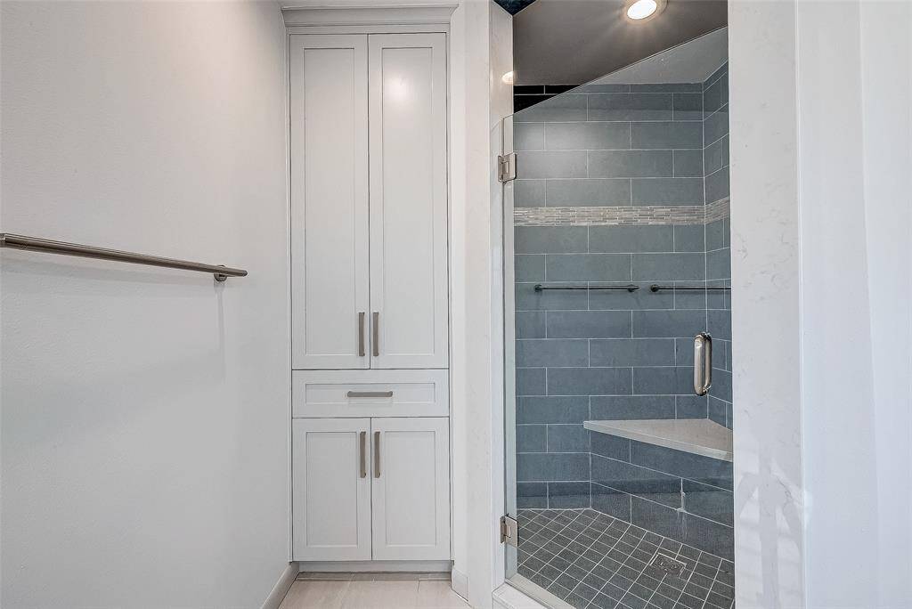 Linen closet and shower with a bench and lighting.