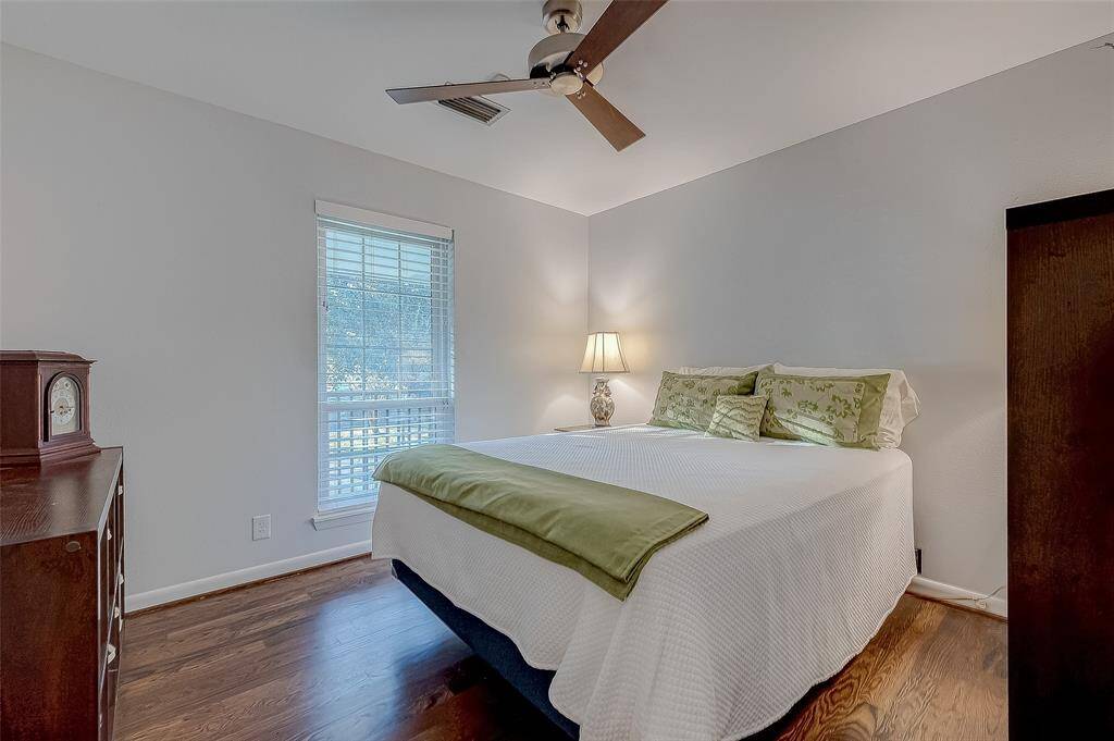 Secondary bedroom has wood floors and a ceiling fan.