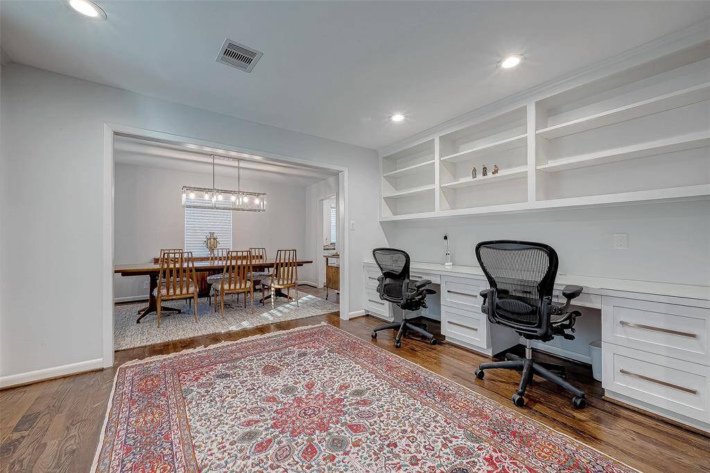 The study has wood floors, a built in desk for two with file cabinets, book shelves and recessed lighting.