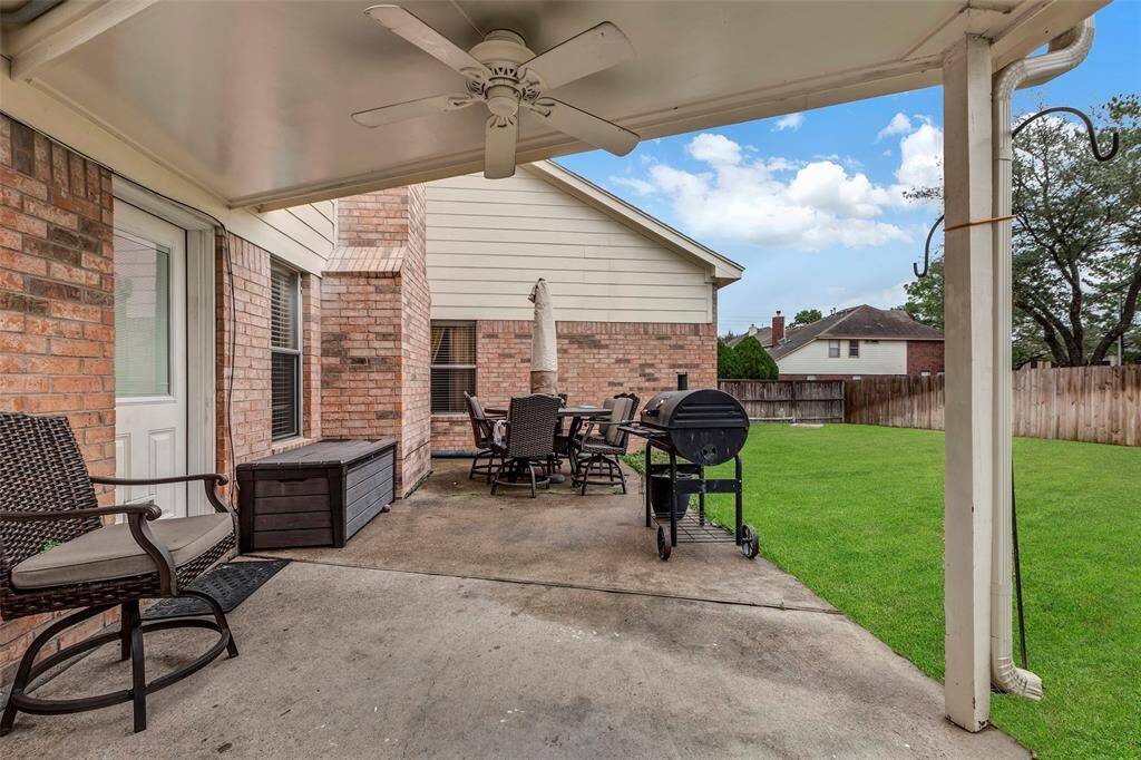Covered Breezeway with ceiling fan. Great view of the oversized back yard. Room for a pool, gardens and play.