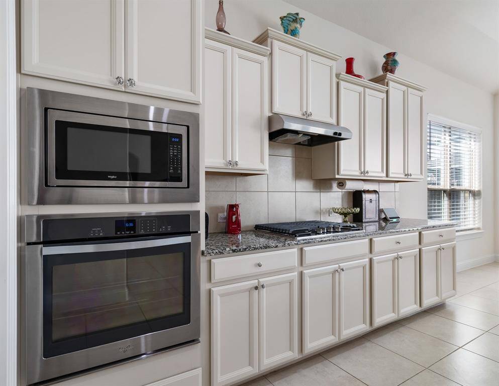 Elegant white cabinets, complemented by granite countertops and tile backsplash.