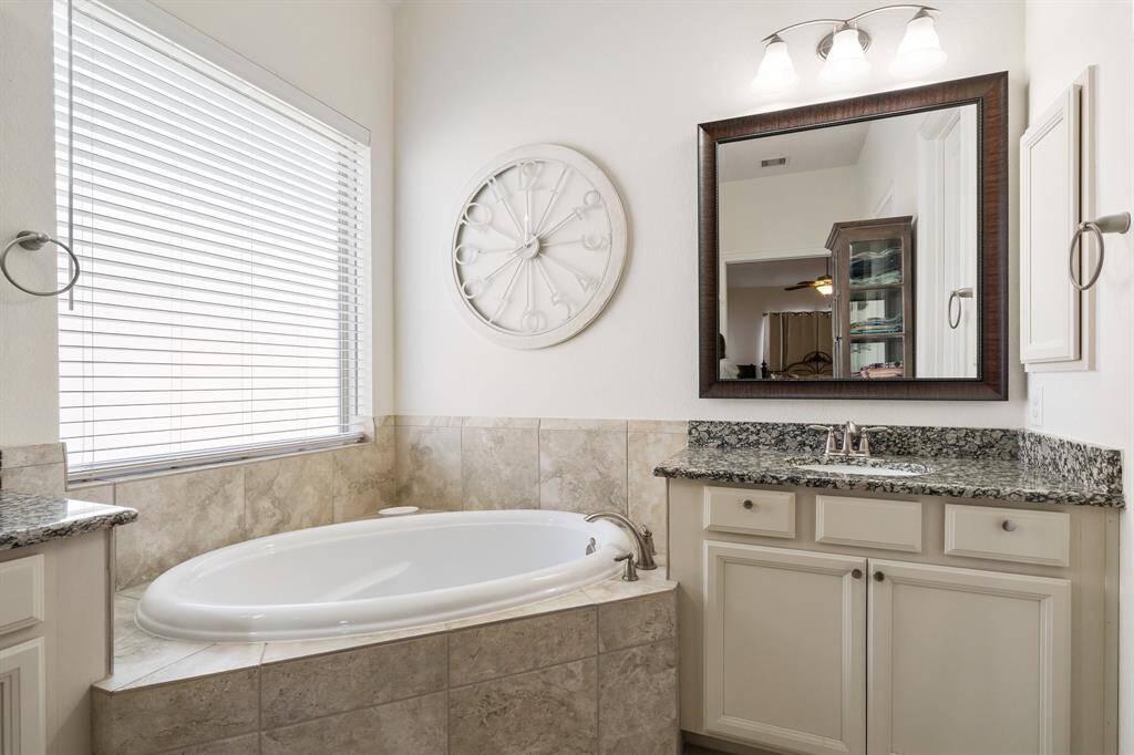 Elegant bathroom features a spacious granite countertop with a large framed mirror, perfect for a luxurious and functional vanity space.