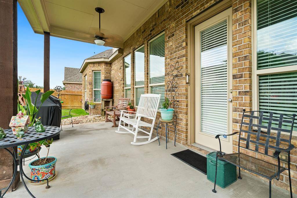 Unwind on the covered patio with ceiling fan, offering a view of the well-maintained backyard.