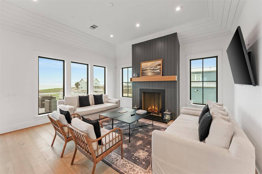 A bright and inviting living room featuring floor-to-ceiling windows, a cozy fireplace, and stunning bay views.