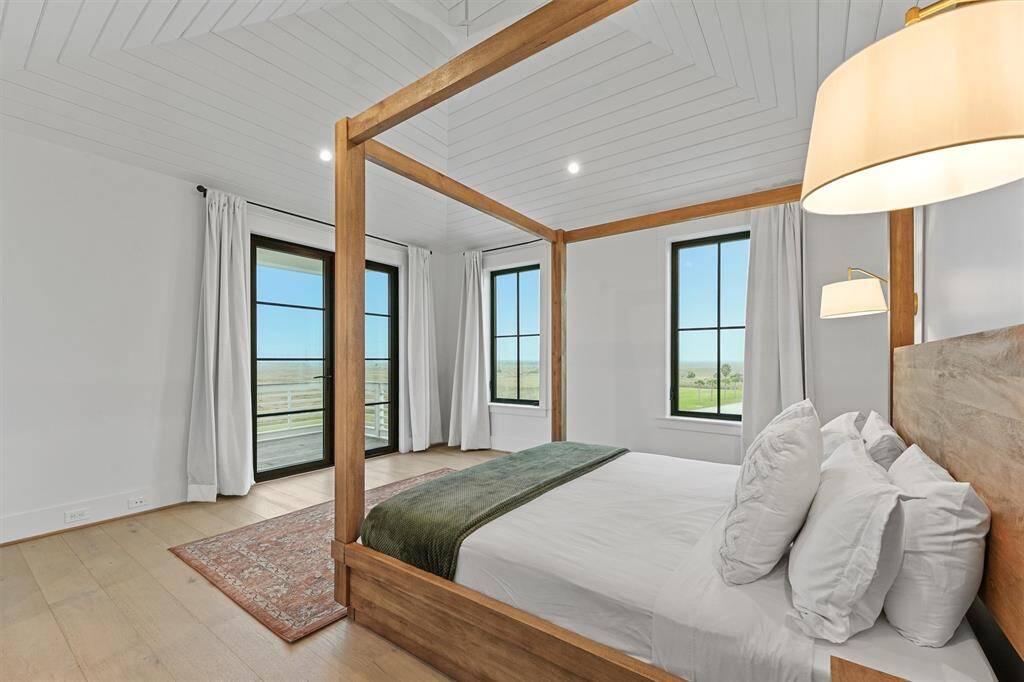 Serene primary bedroom retreat with a custom wood canopy bed, vaulted shiplap ceilings, and private deck access with breathtaking views.