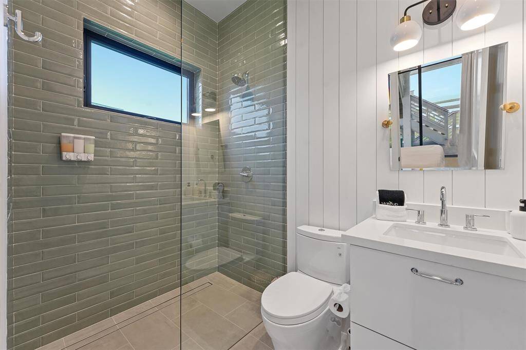 Beautifully designed ensuite featuring a walk-in glass shower, elegant green subway tiles, and modern fixtures.