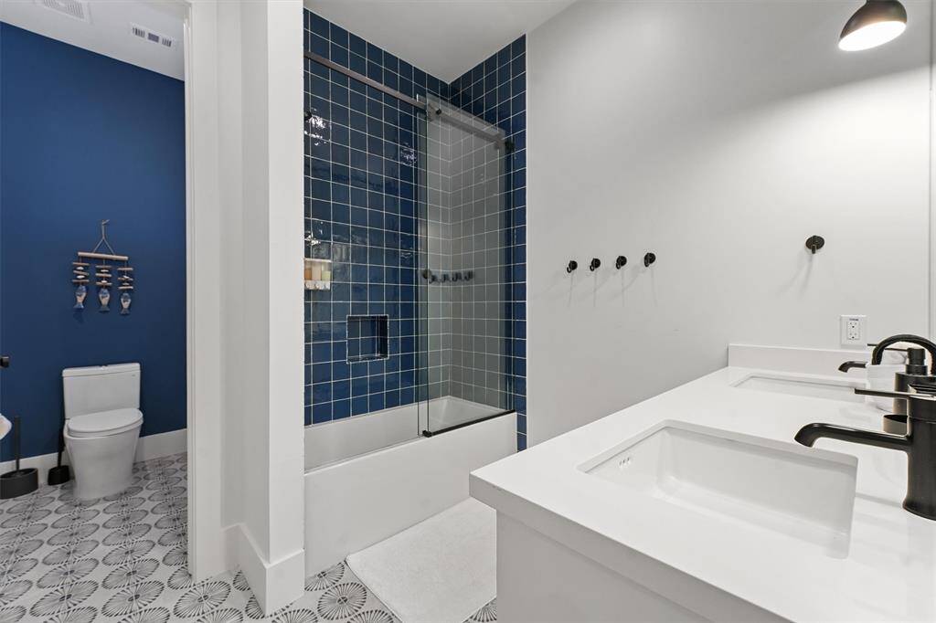 Elegant bathroom with bold navy tiles, double vanity, and stylish black fixtures.