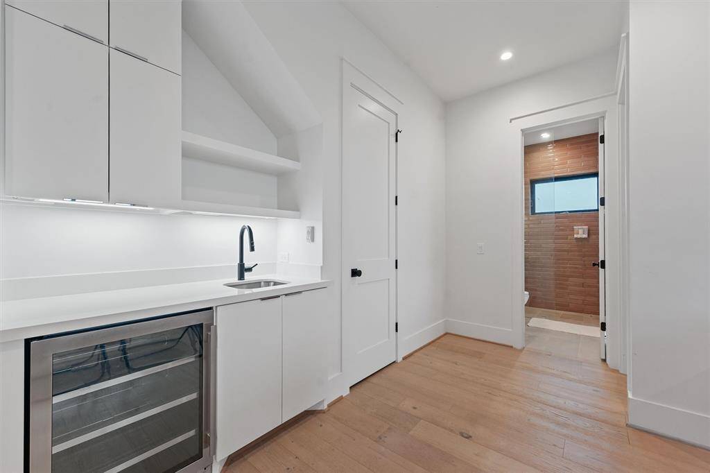 Convenient wet bar with sleek cabinetry, a wine cooler, and easy access to the adjacent bath for ultimate guest comfort.
