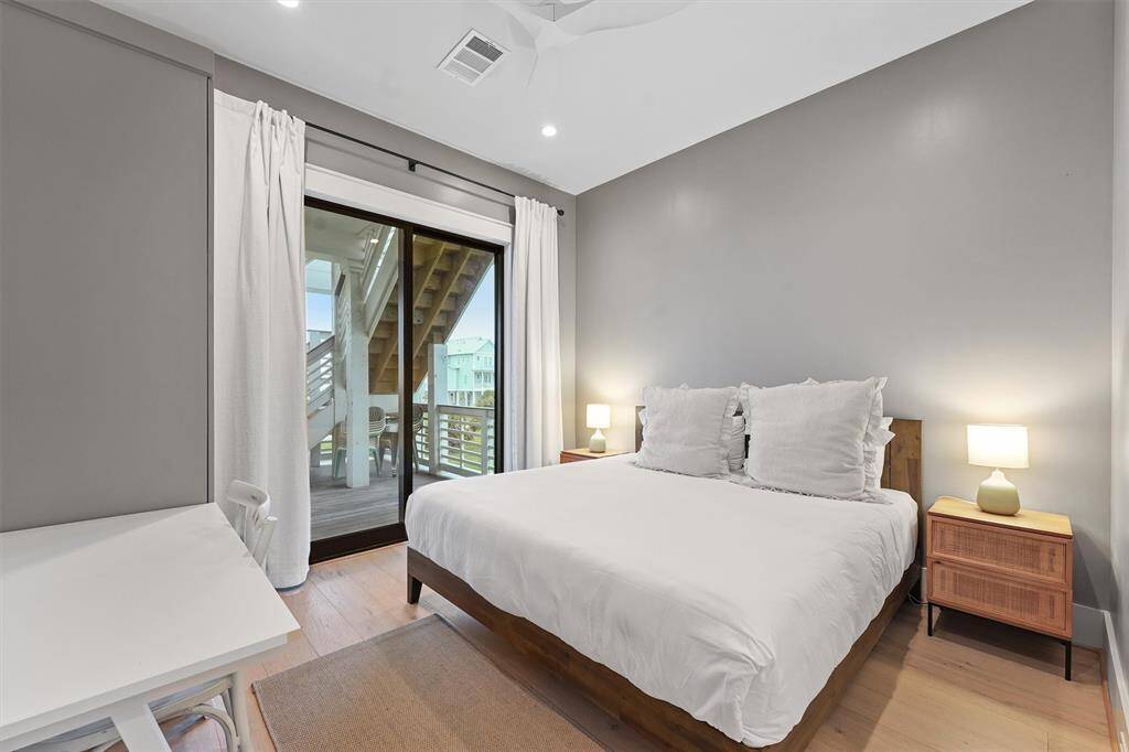 Charming bedroom with dual beds, a dedicated workspace, and sliding door access to a private deck with bay views.