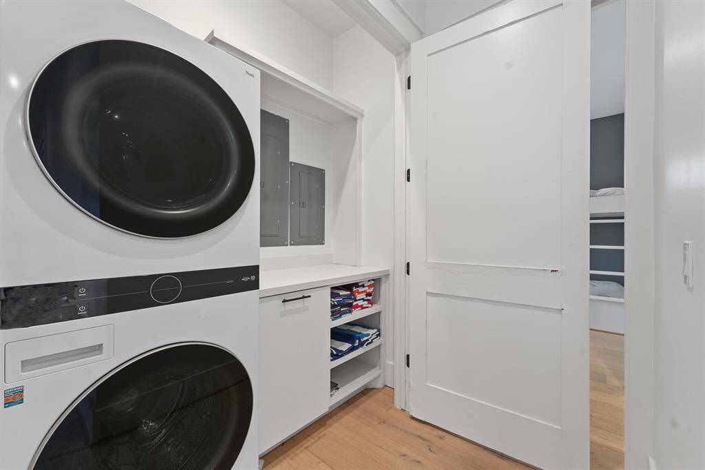 Well-equipped laundry room with a sleek stacked washer and dryer, built-in storage, and modern functionality.