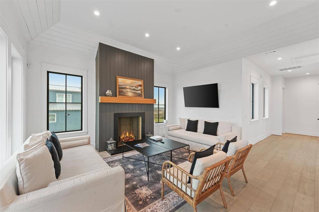 Modern coastal elegance with an open-concept design, warm wood flooring, and a striking fireplace as the focal point.