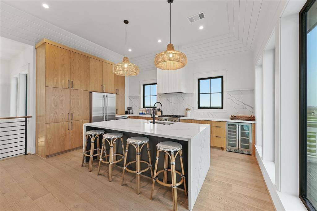 Sleek and modern kitchen featuring custom wood cabinetry, quartz countertops, and chic woven pendant lighting.