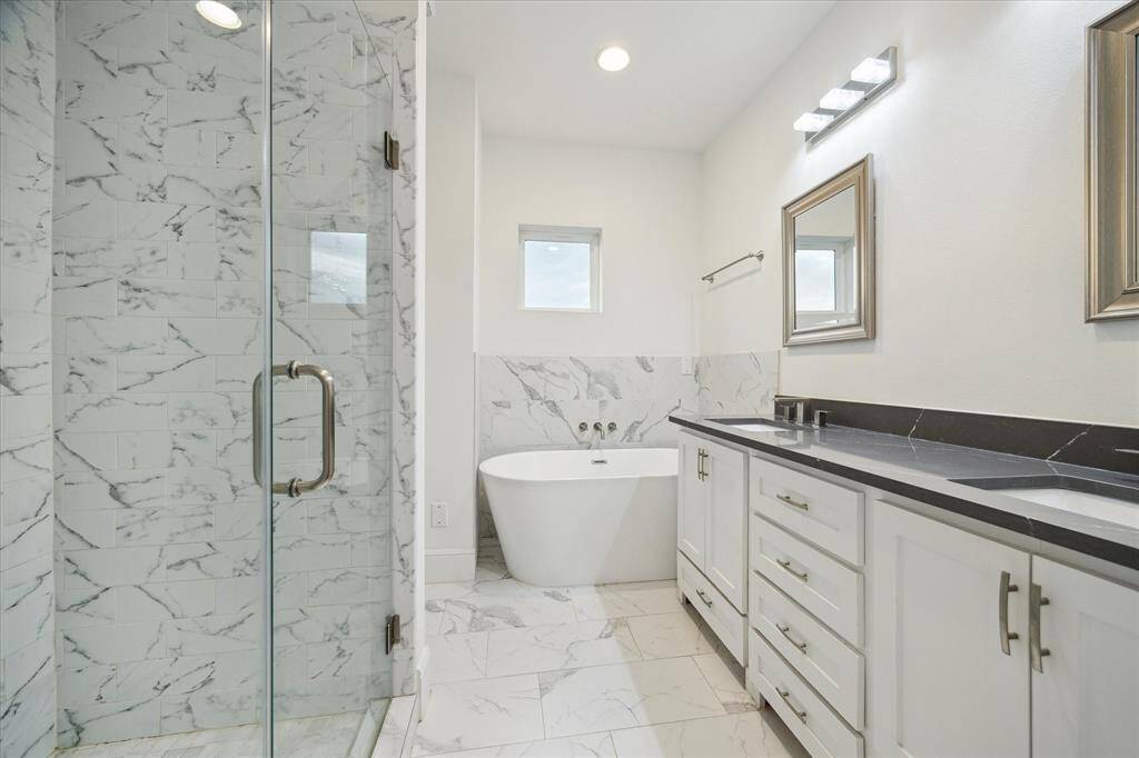 primary bath, porcelain tiles, quartz stone, large soaking tub, walk in closet with custom built ins not seen in photo.