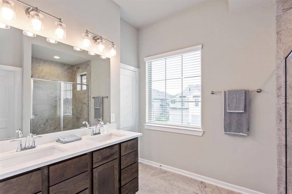 Primary Bath with double sinks, and quartz countertops.  Gorgeous natural lighting beams through the window eliminating the room.
