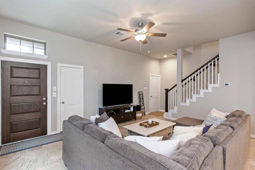 The living room space is enhanced by neutral tones, a welcoming front door, and a staircase leading to the upper level. Ideal for relaxation and family gatherings.