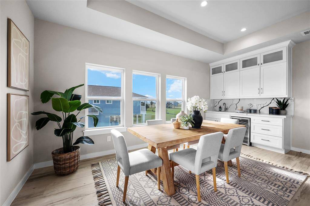 Large windows frame the scenic outdoor views, while the open layout seamlessly connects to the kitchen and nearby wet bar for effortless entertaining