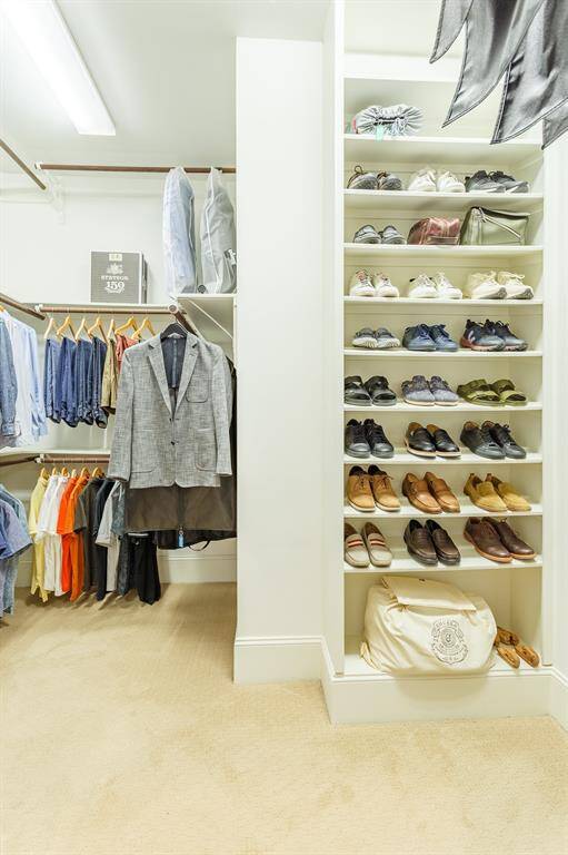 A spacious walk-in closet with ample shelving for shoes and plenty of hanging space for clothes, offering a bright and functional storage solution.